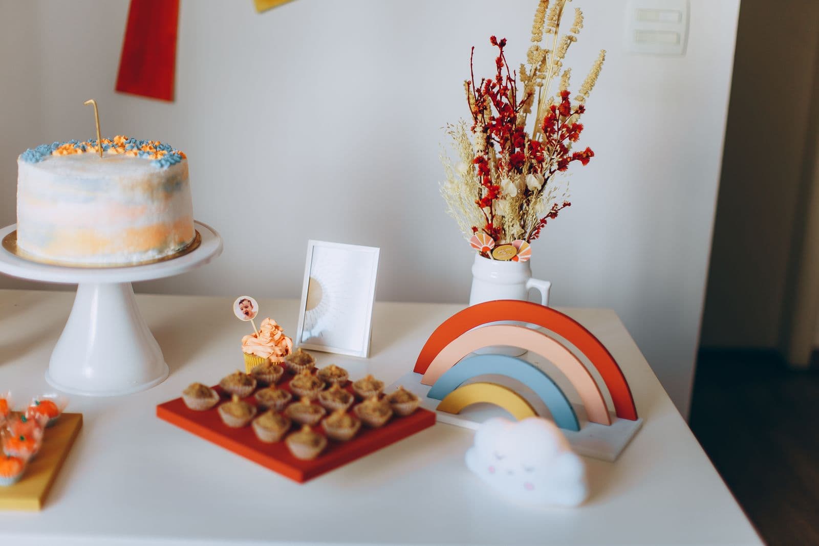 A vibrant dessert table with a decorated cake, cupcakes, and coordinated pastel decorations