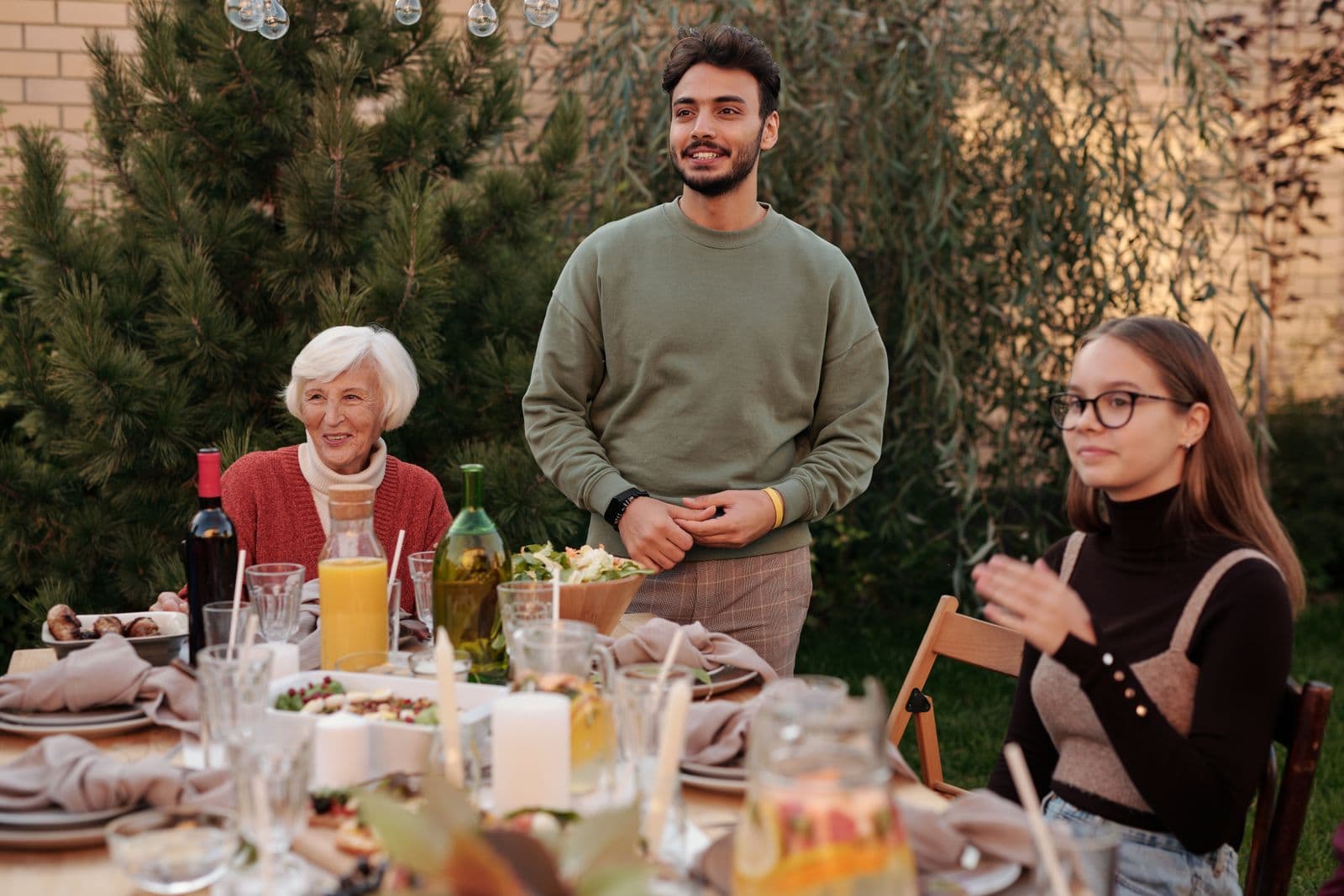 A large family gathered and talking together around an outdoor dinner table