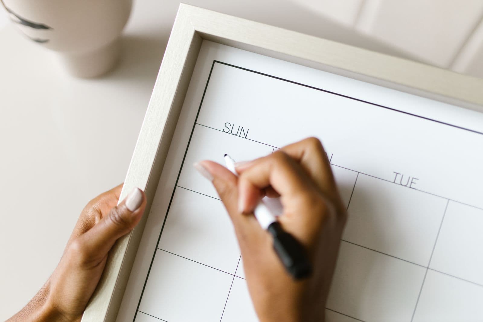 A person marking dates on a blank wall calendar