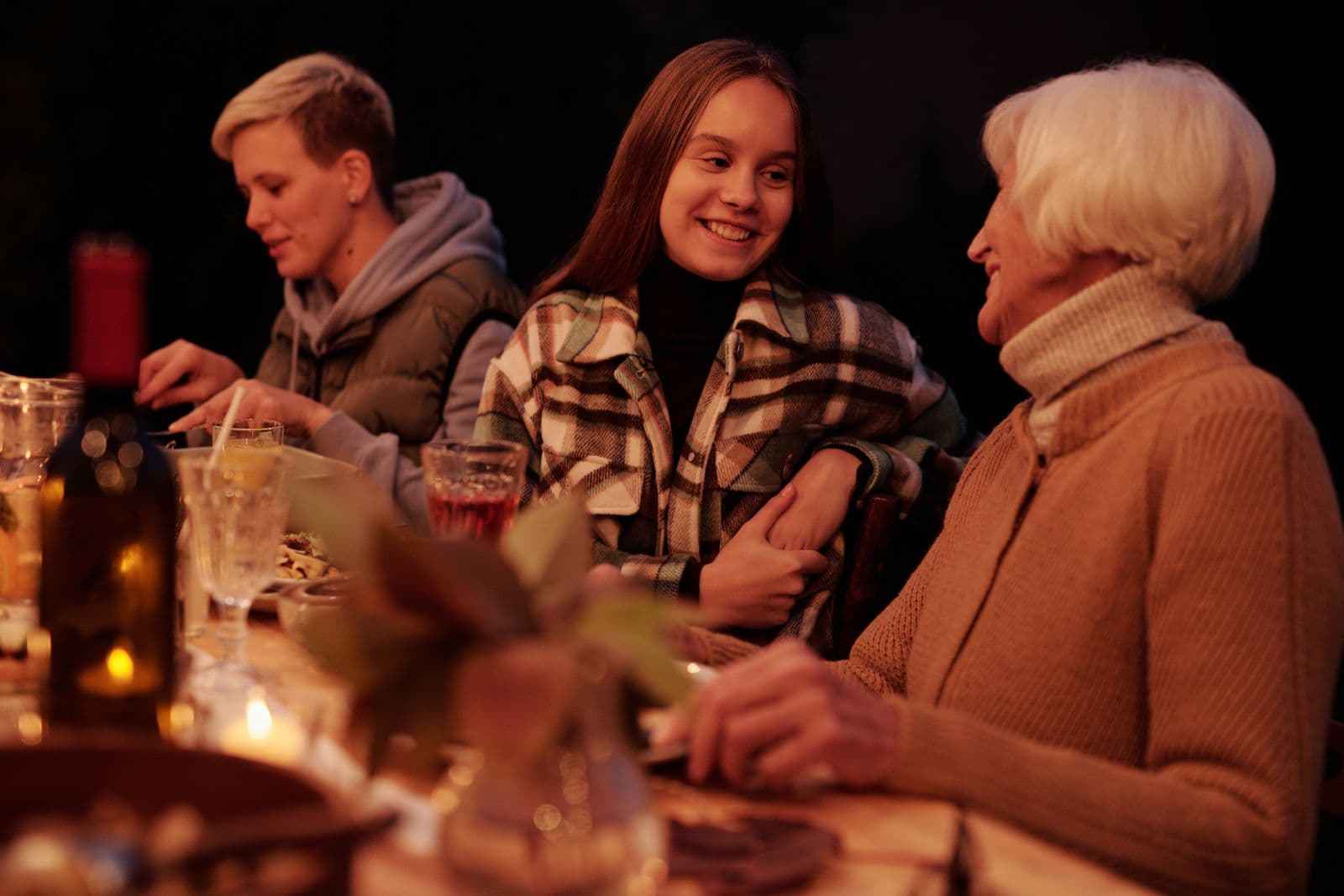 A young girl and her grandmother talking closely at an outdoor family table