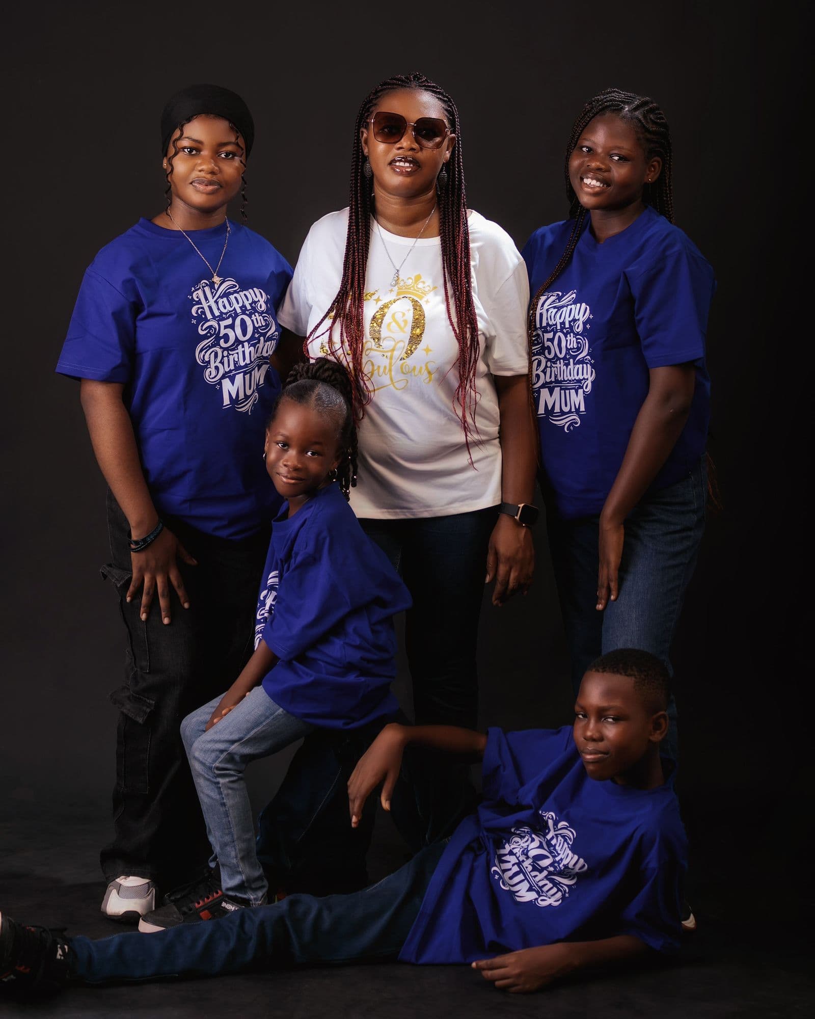 A family posing together outdoors, all wearing matching coordinated shirts for a birthday celebration