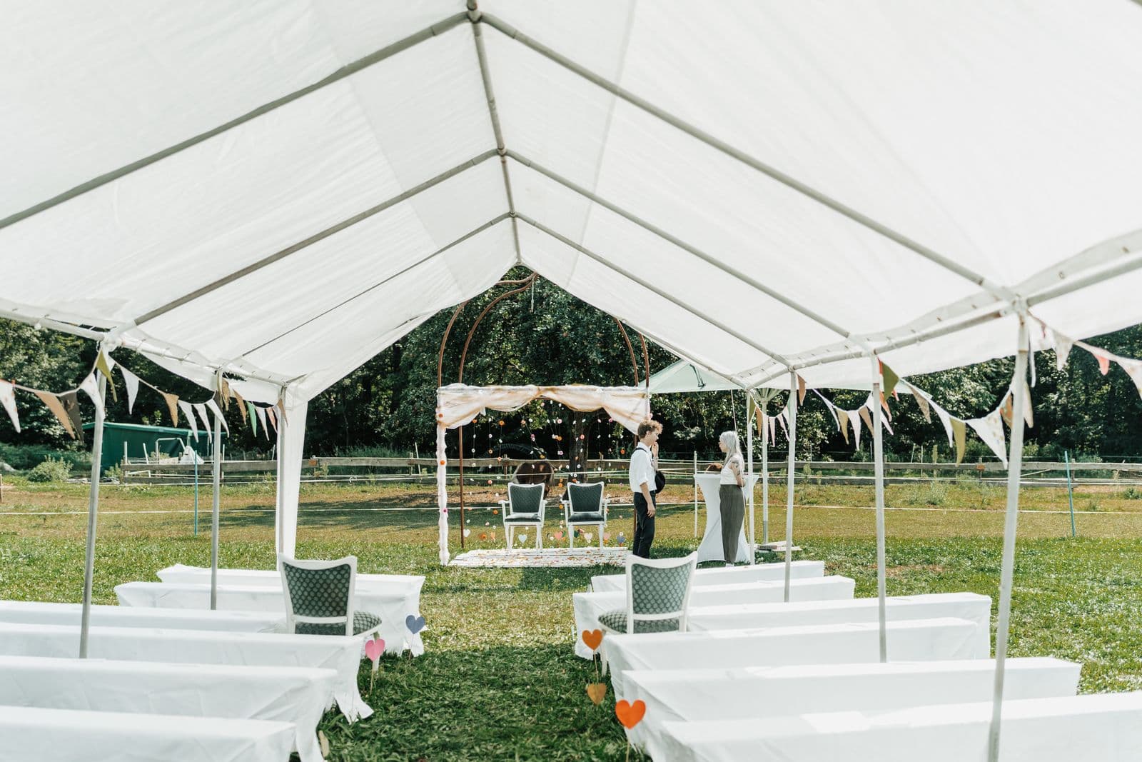 An outdoor event setup with chairs and decorations under a white tent