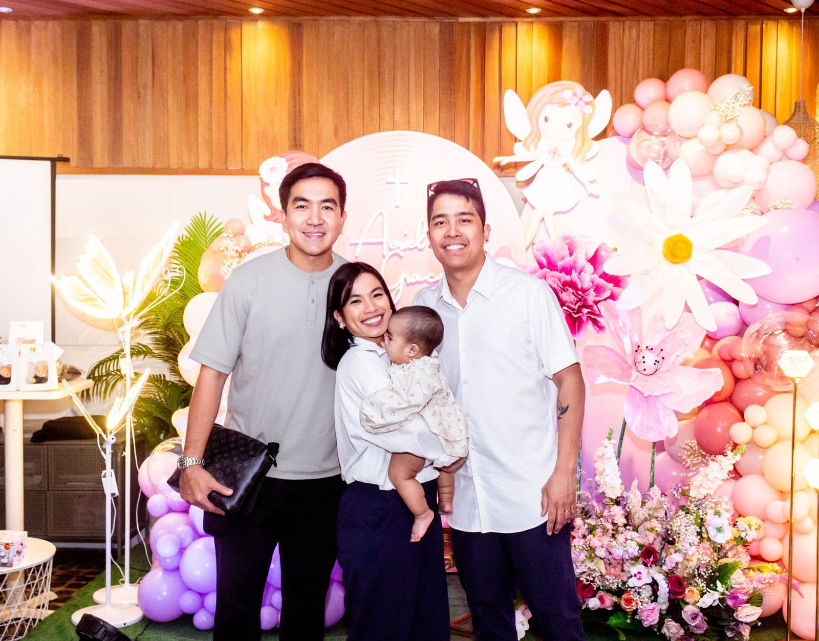 A family posing for photos in front of an elaborate balloon and floral photo booth backdrop