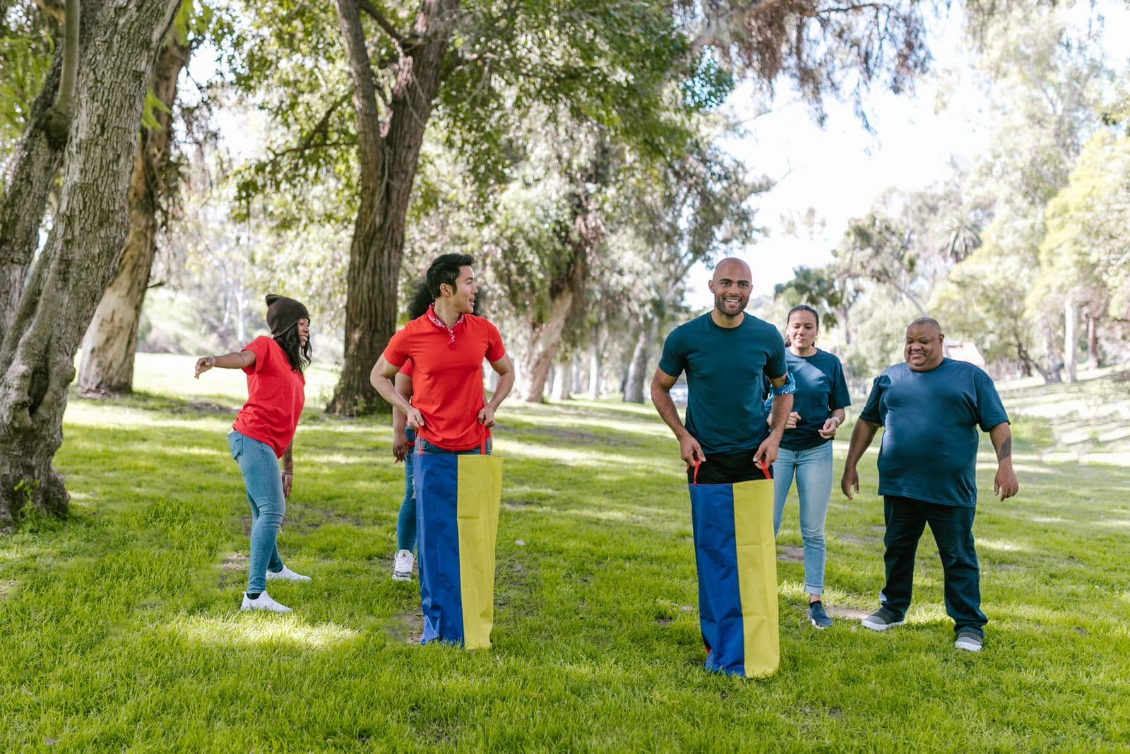 A group of coworkers laughing during an outdoor sack race at a team-building event