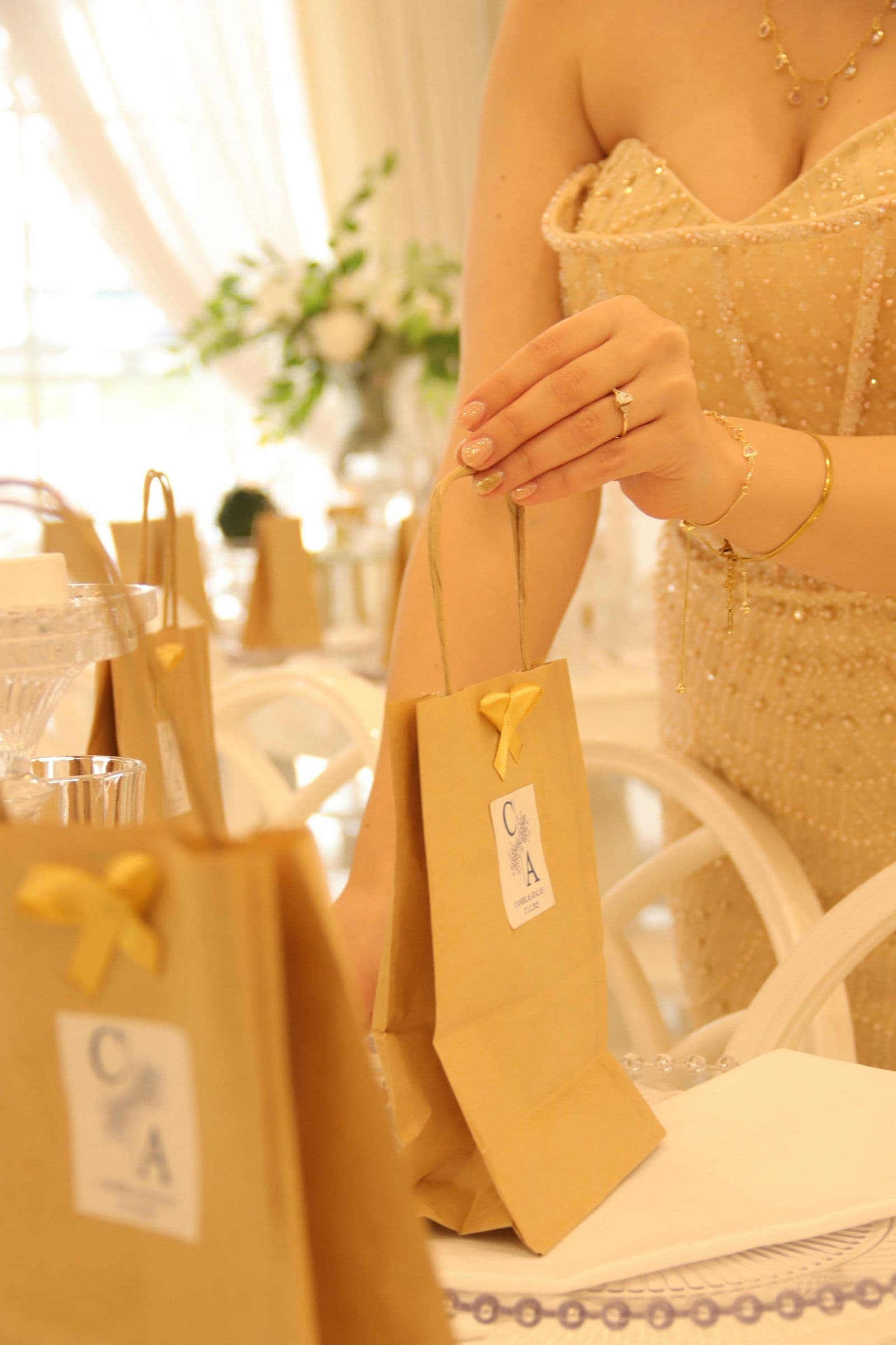 A woman carefully arranging gift bags on a table at an elegant indoor wedding reception